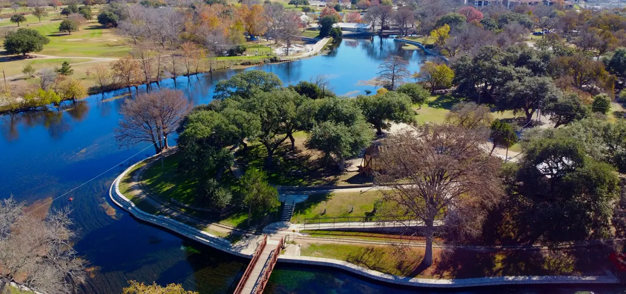 Aerial view of Landa Park, New Braunfels: the spring-fed lake, oaks, golf course, and red footbridge